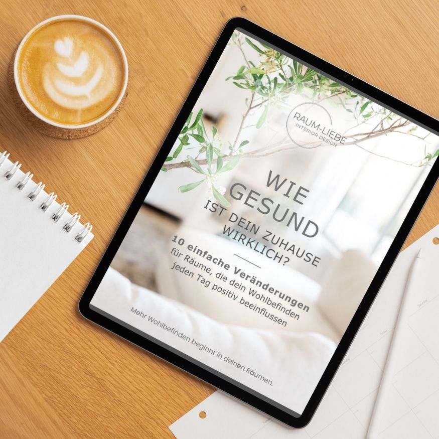 Tablet mit Freebie-Guide auf Holztisch neben Notizblock und Cappuccino